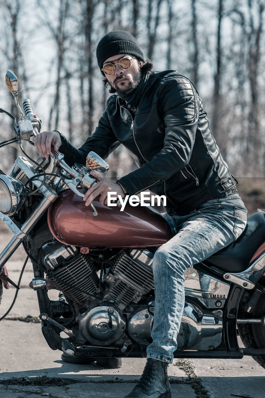 Mid adult man sitting on motorcycle in forest