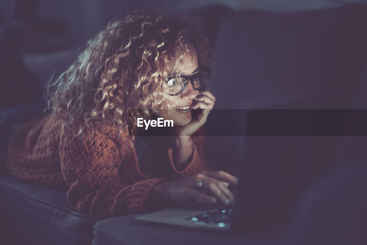 Woman using laptop while sitting on sofa at home