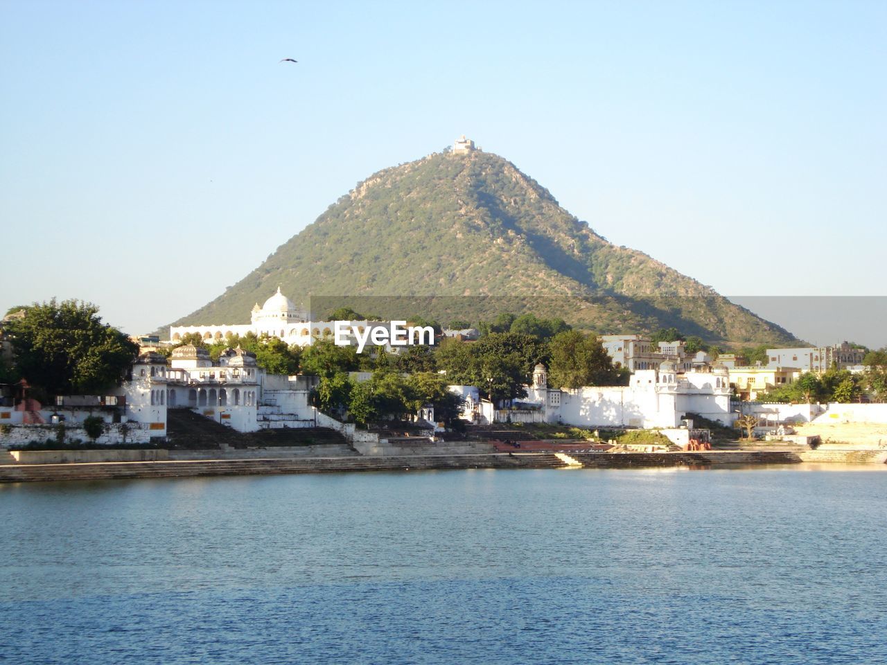 Buildings by sea against clear sky