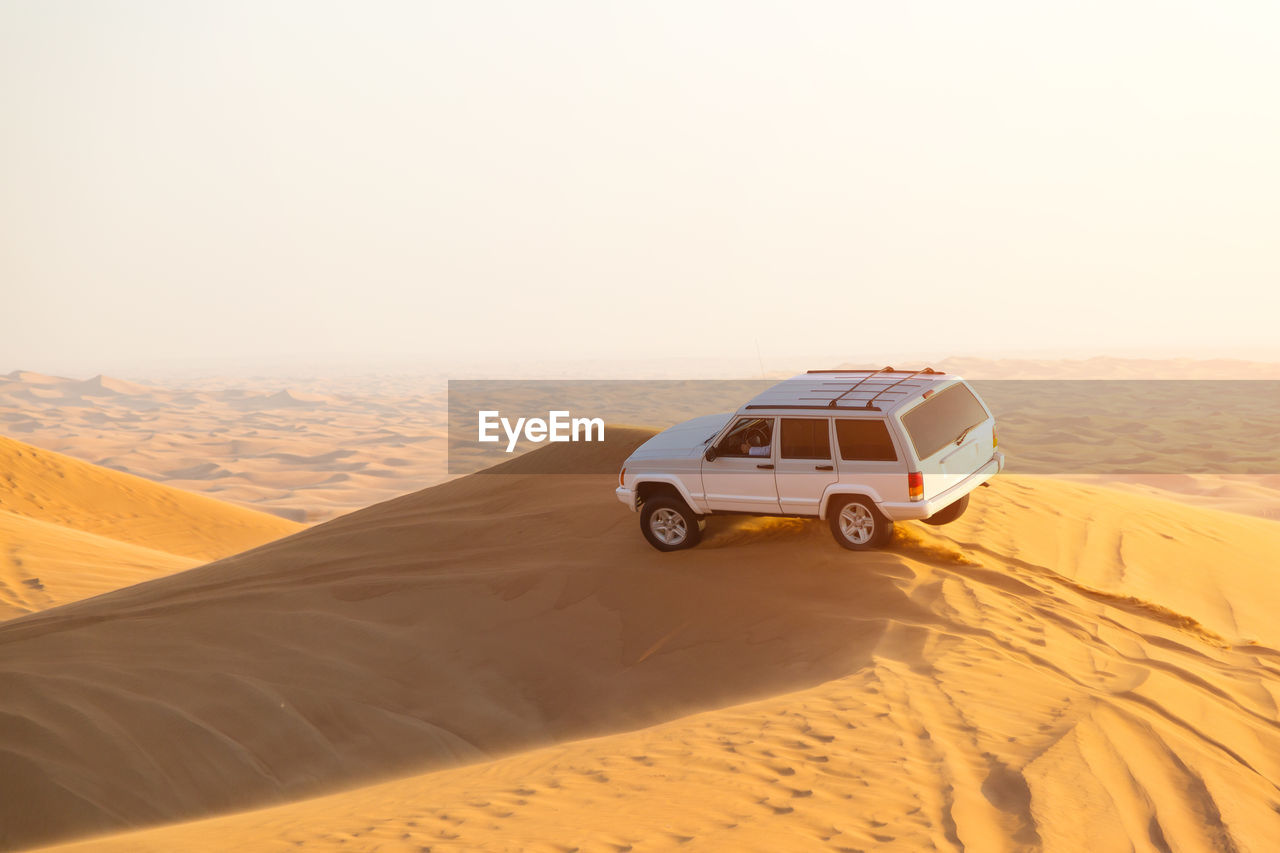 Car on desert against clear sky