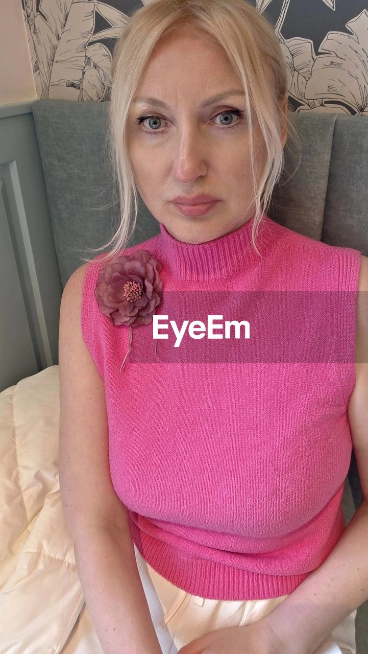 pink, blond hair, women, one person, adult, indoors, portrait, clothing, looking at camera, furniture, human hair, front view, hairstyle, sitting, domestic room, lifestyles, female, human face, waist up, home interior, three quarter length, person, domestic life, young adult, undergarment, sofa, panties, hand, human mouth