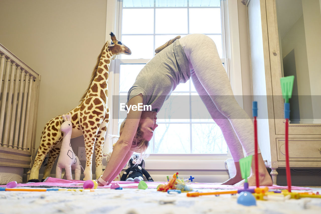 Young mom in downward dog yoga position in daughter's room
