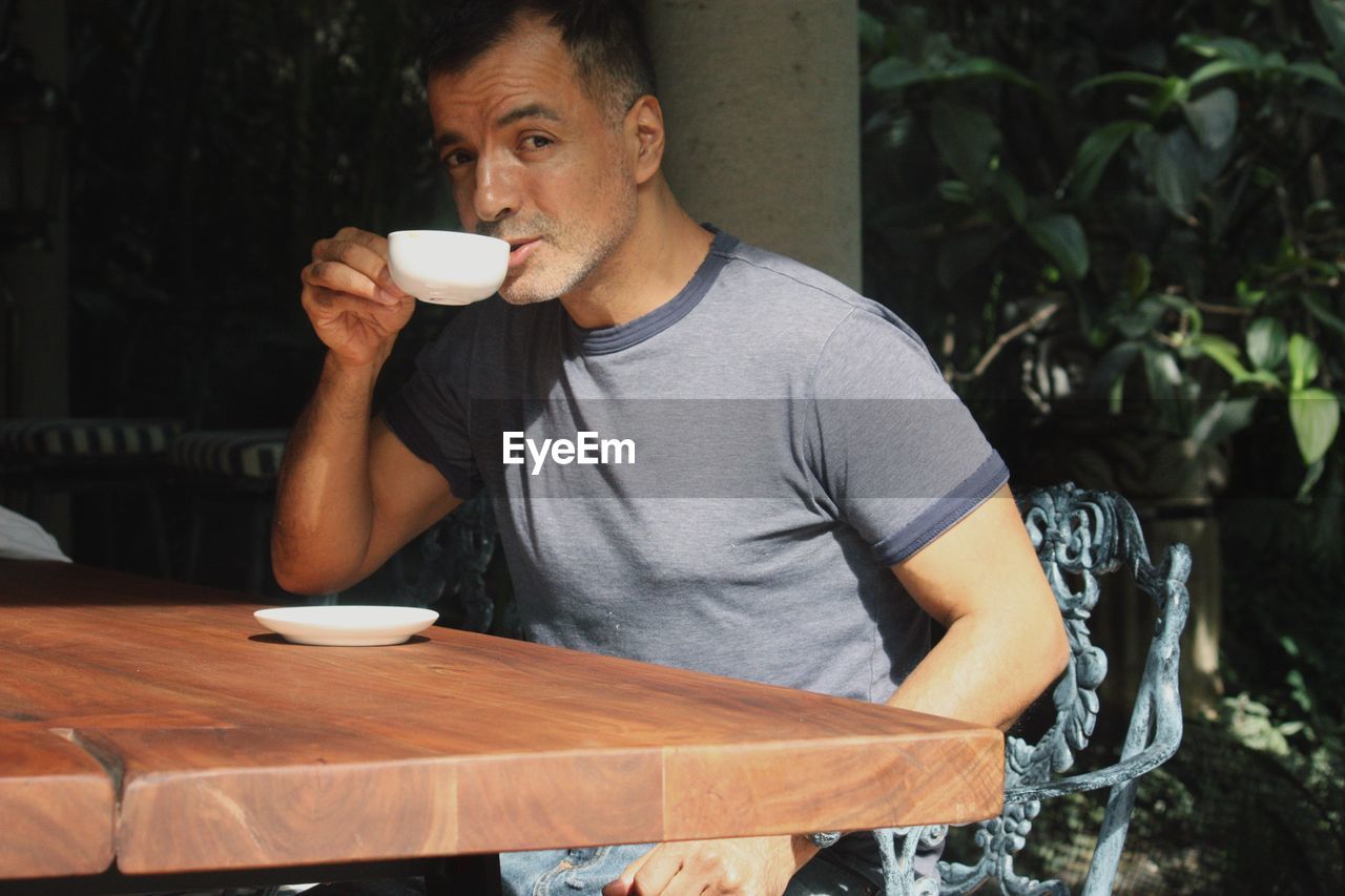 Portrait of man drinking coffee in back yard