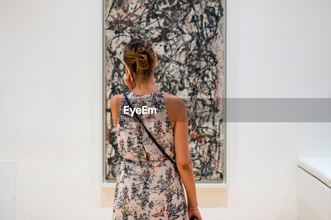 WOMAN STANDING AGAINST WALL IN ROOM