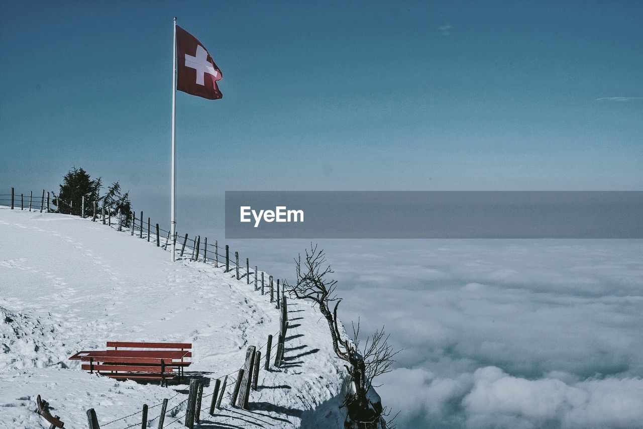 Swiss flag on mountain by cloud covering landscape