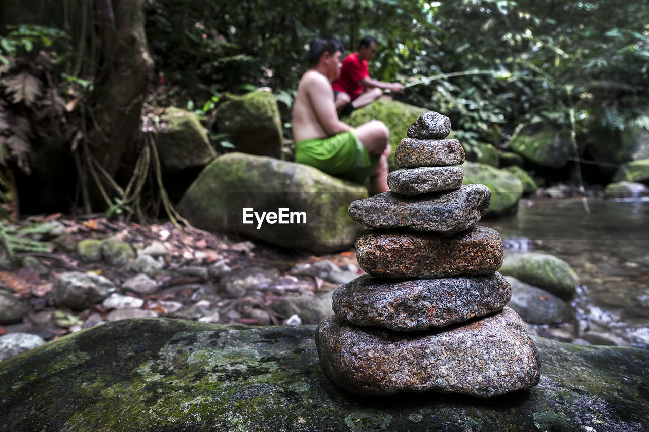 Stack of stones in stream with people fishing in background