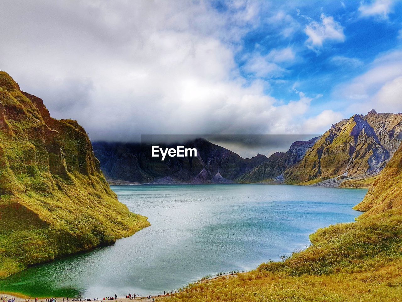 Scenic view of lake and mountains against cloudy sky