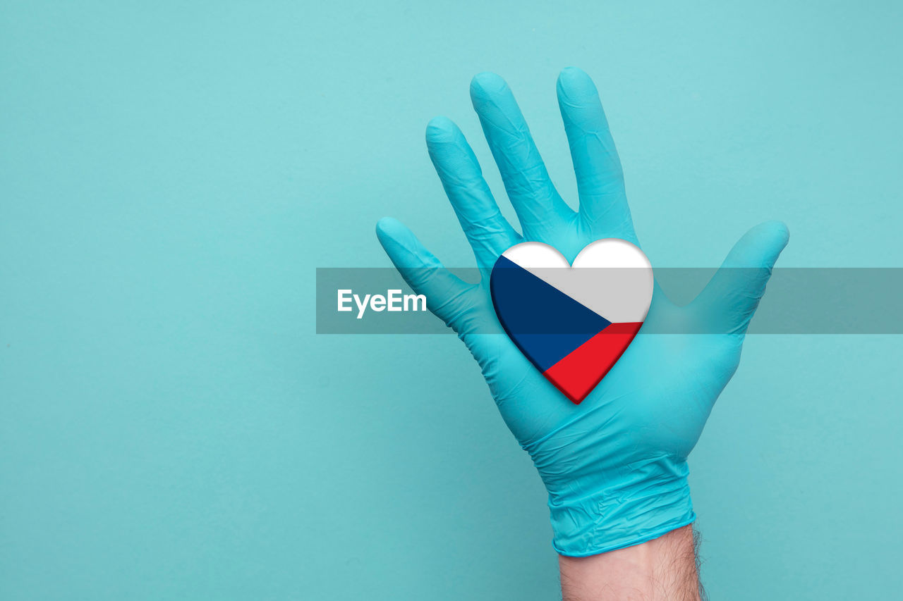 CLOSE-UP OF HUMAN HAND HOLDING BLUE BACKGROUND