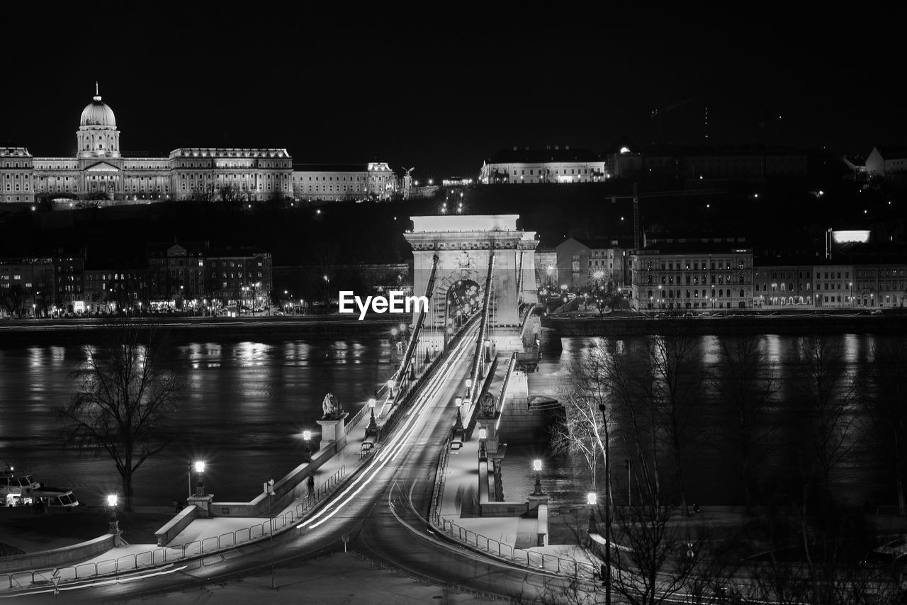 ILLUMINATED BRIDGE OVER RIVER AGAINST SKY