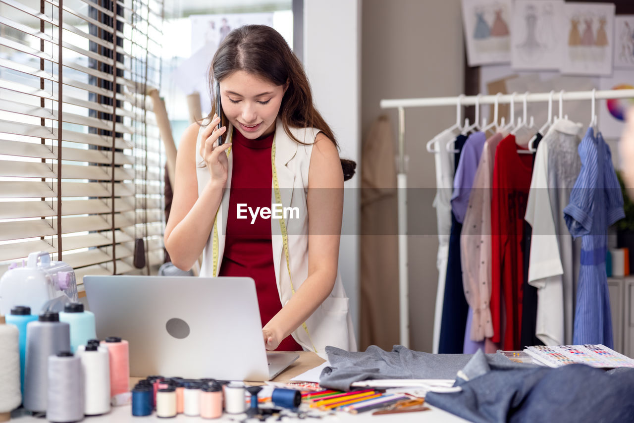 Millennial woman dressmaker making a phone call to her partner while holding . 