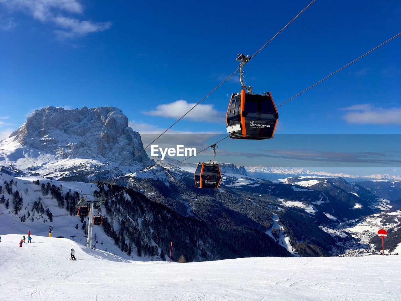 OVERHEAD CABLE CARS OVER SNOW COVERED MOUNTAINS