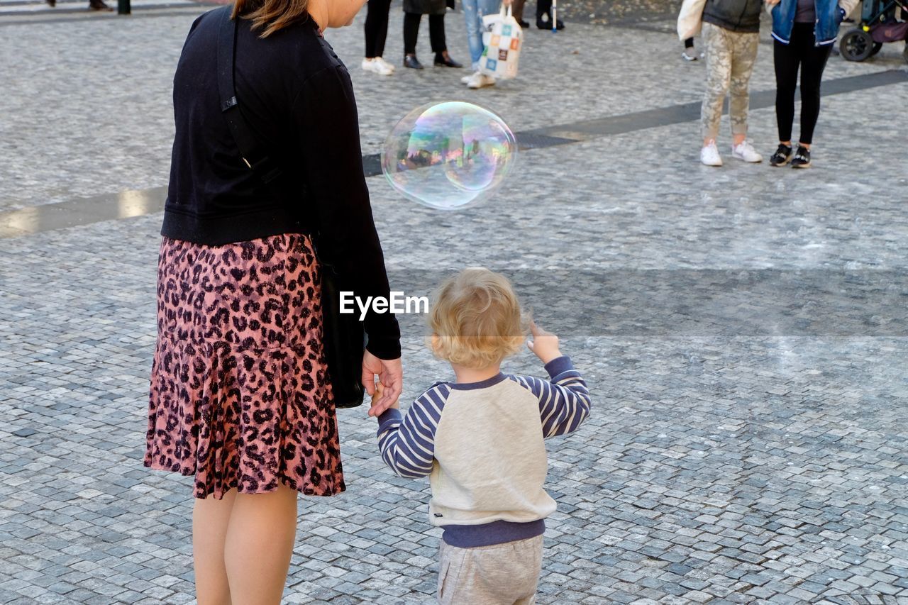 Mother and child standing by bubble on street in city