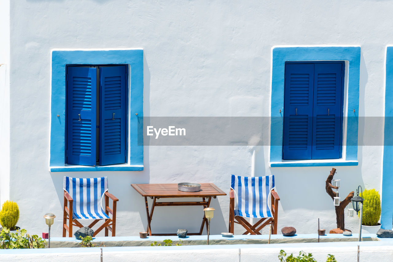 CHAIRS AND TABLES AGAINST BLUE WALL OF HOUSE