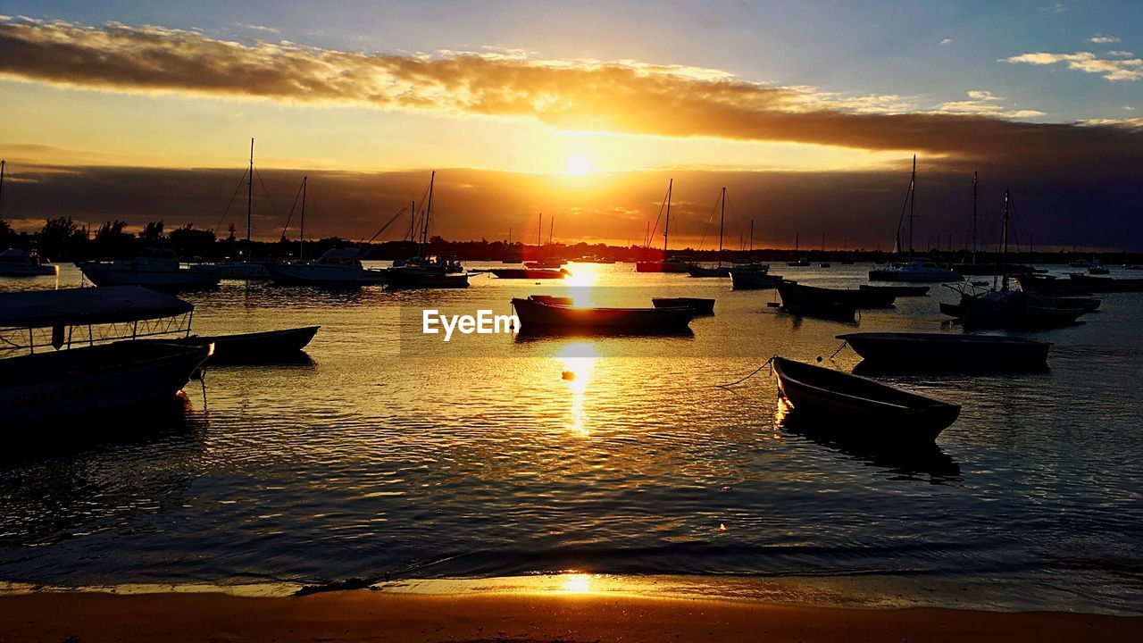 BOATS MOORED IN SEA AGAINST SKY DURING SUNSET