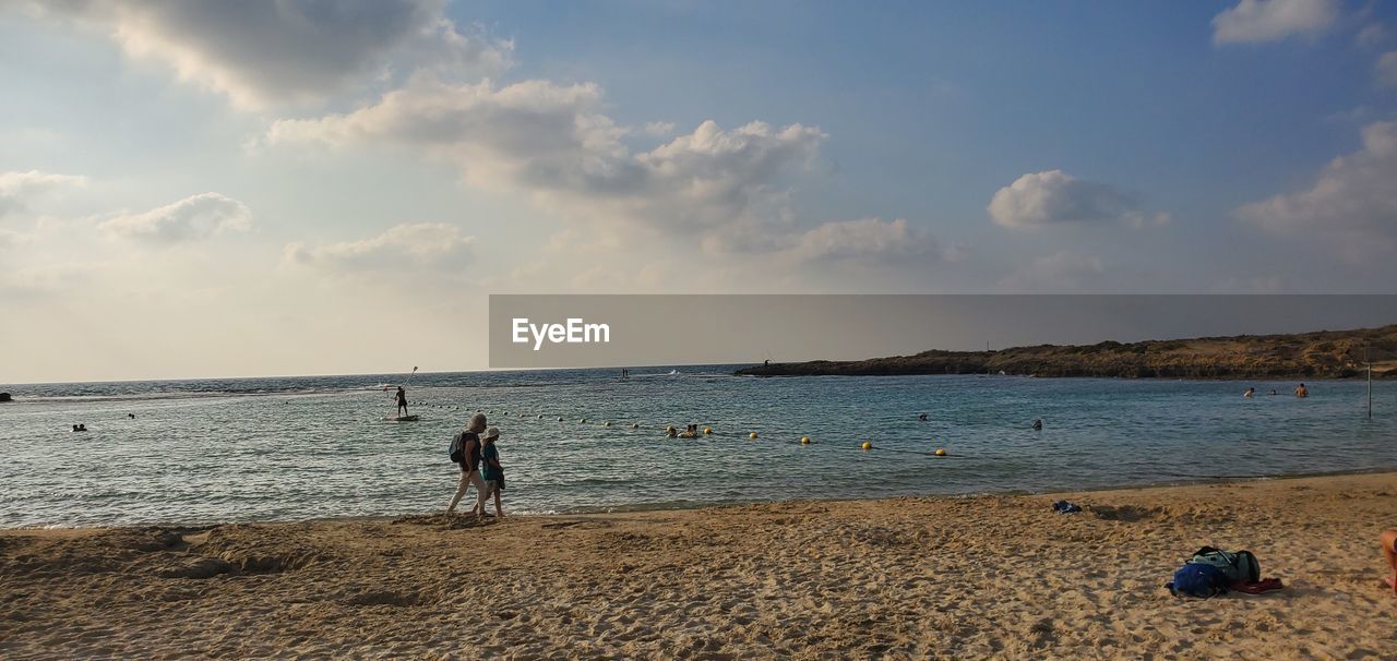MEN ON BEACH AGAINST SKY
