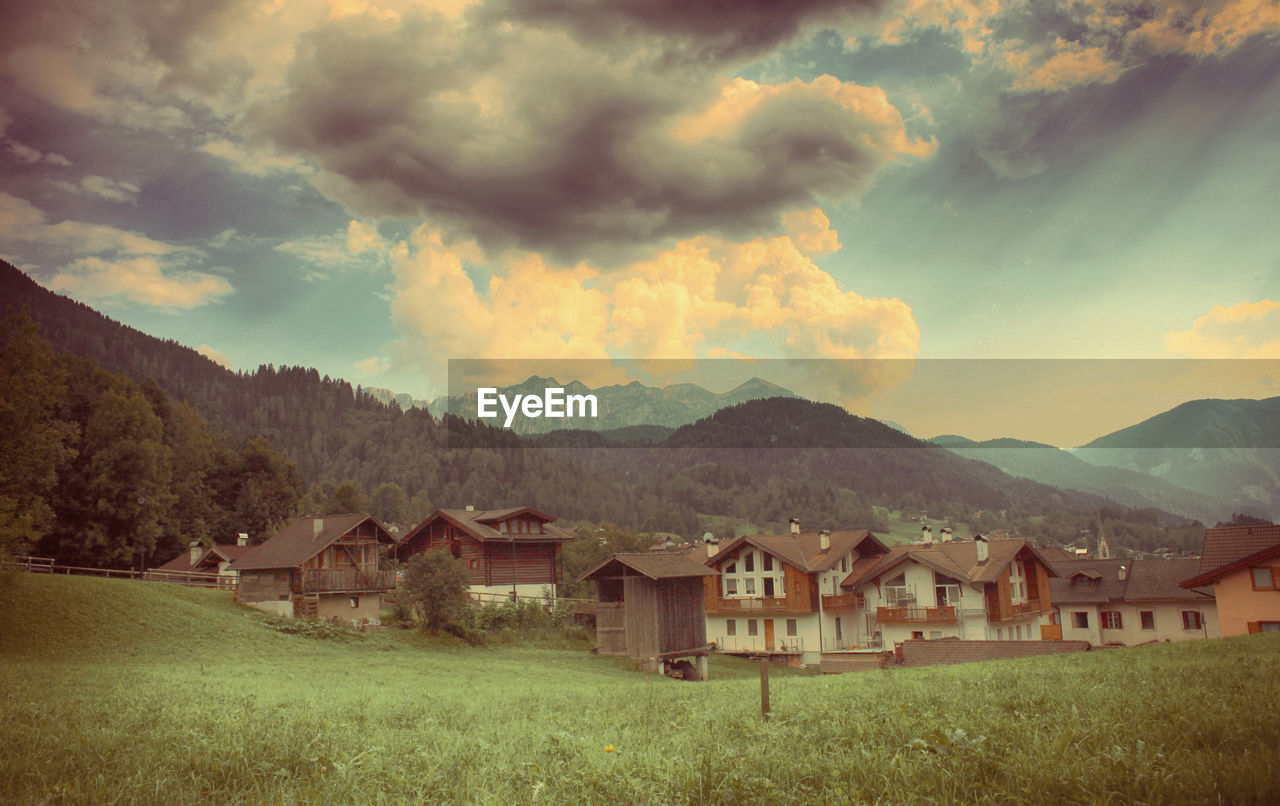 Houses on field by mountains against sky