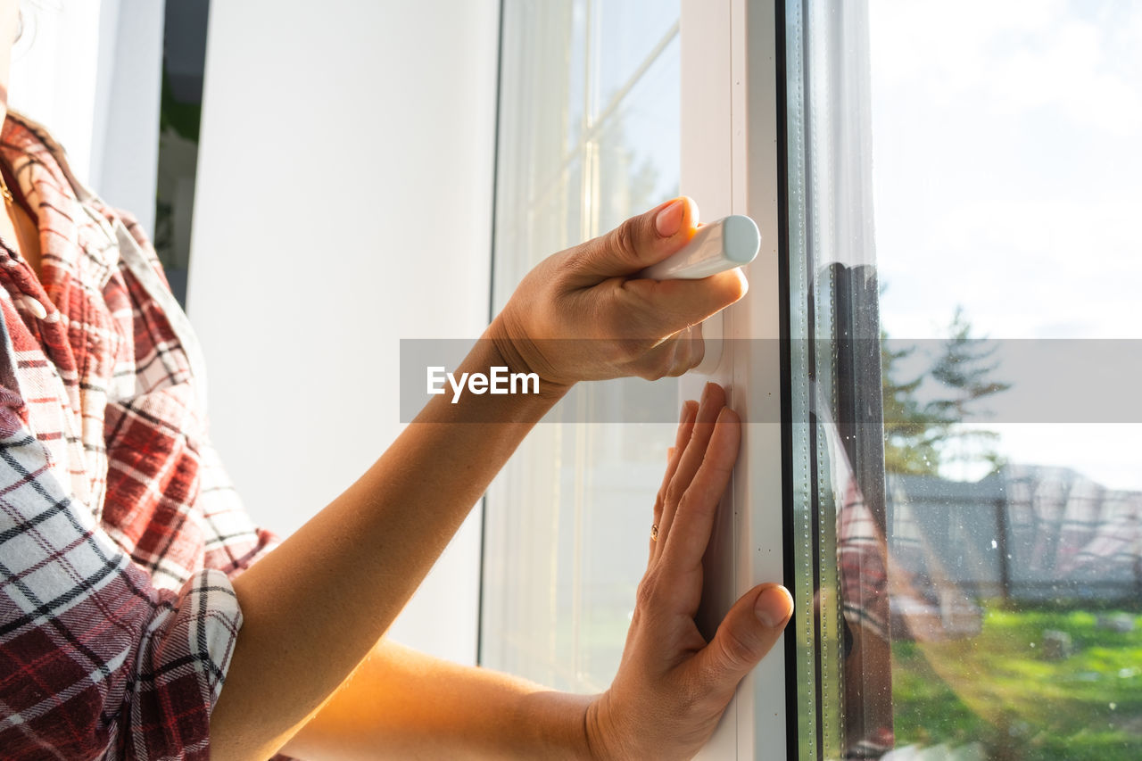 cropped image of woman holding window