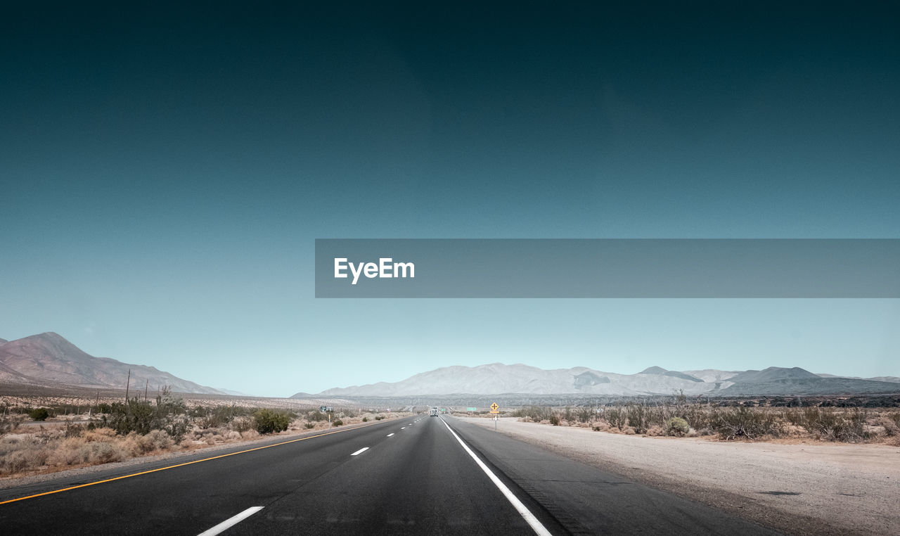 Empty road along landscape against clear sky