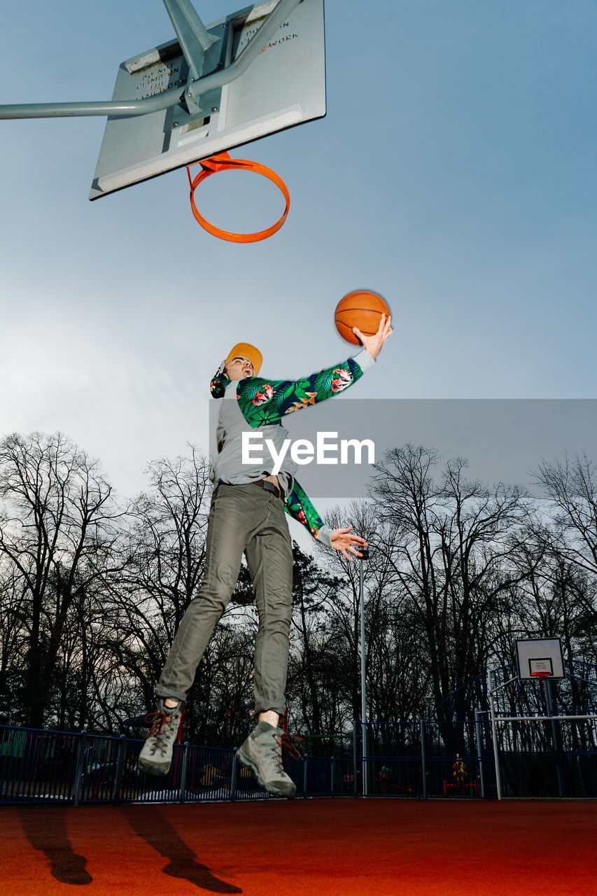 Low angle view of man playing basketball against sky