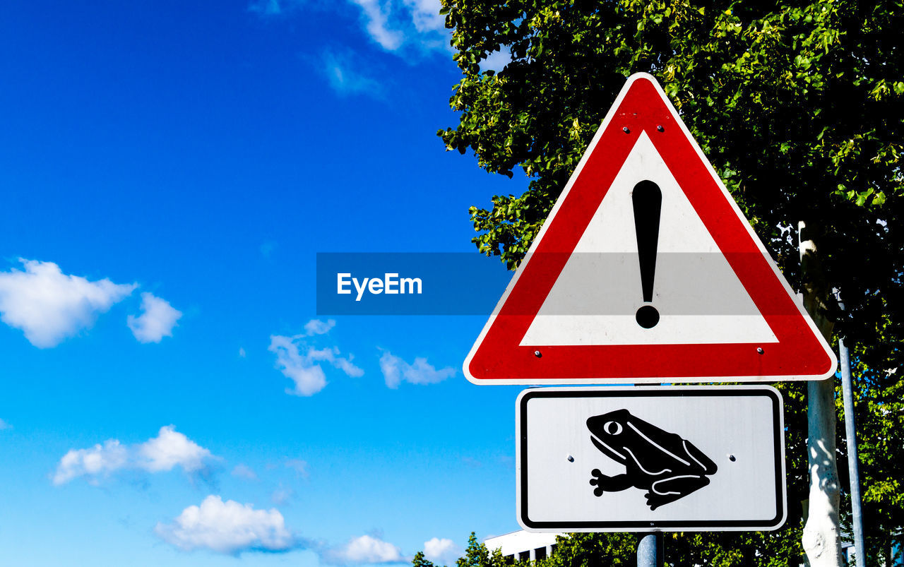 Close-up of road sign against blue sky