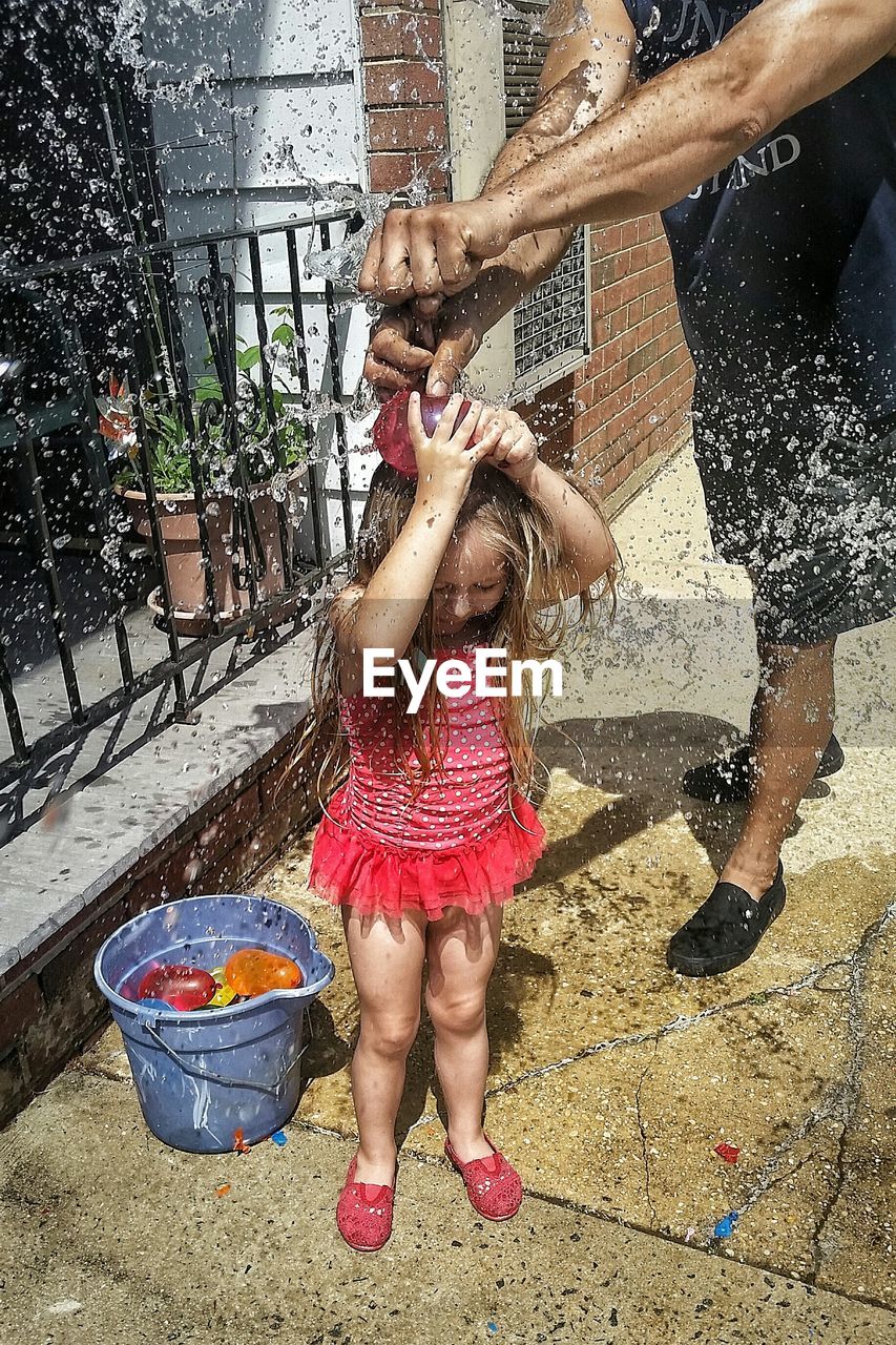 Cropped image of man playing water bomb with daughter