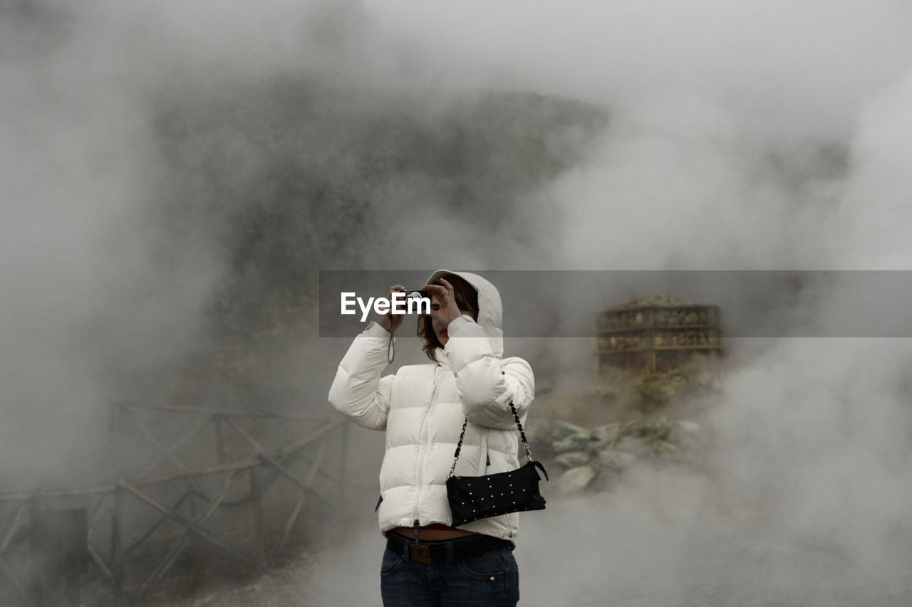 MAN HOLDING CAMERA STANDING ON TELEPHONE POLE