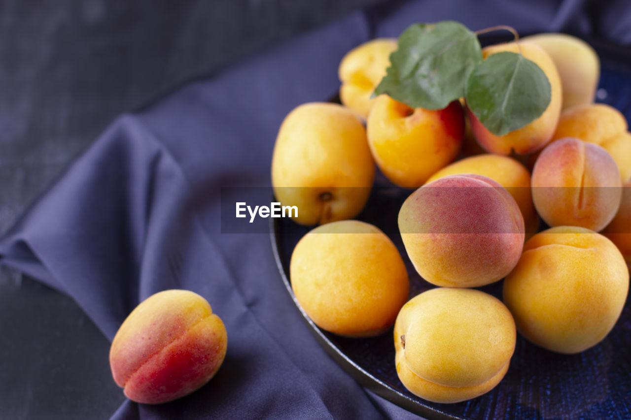 Fresh apricot on a dark silk fabric. ripe sweet berries in droplets of water