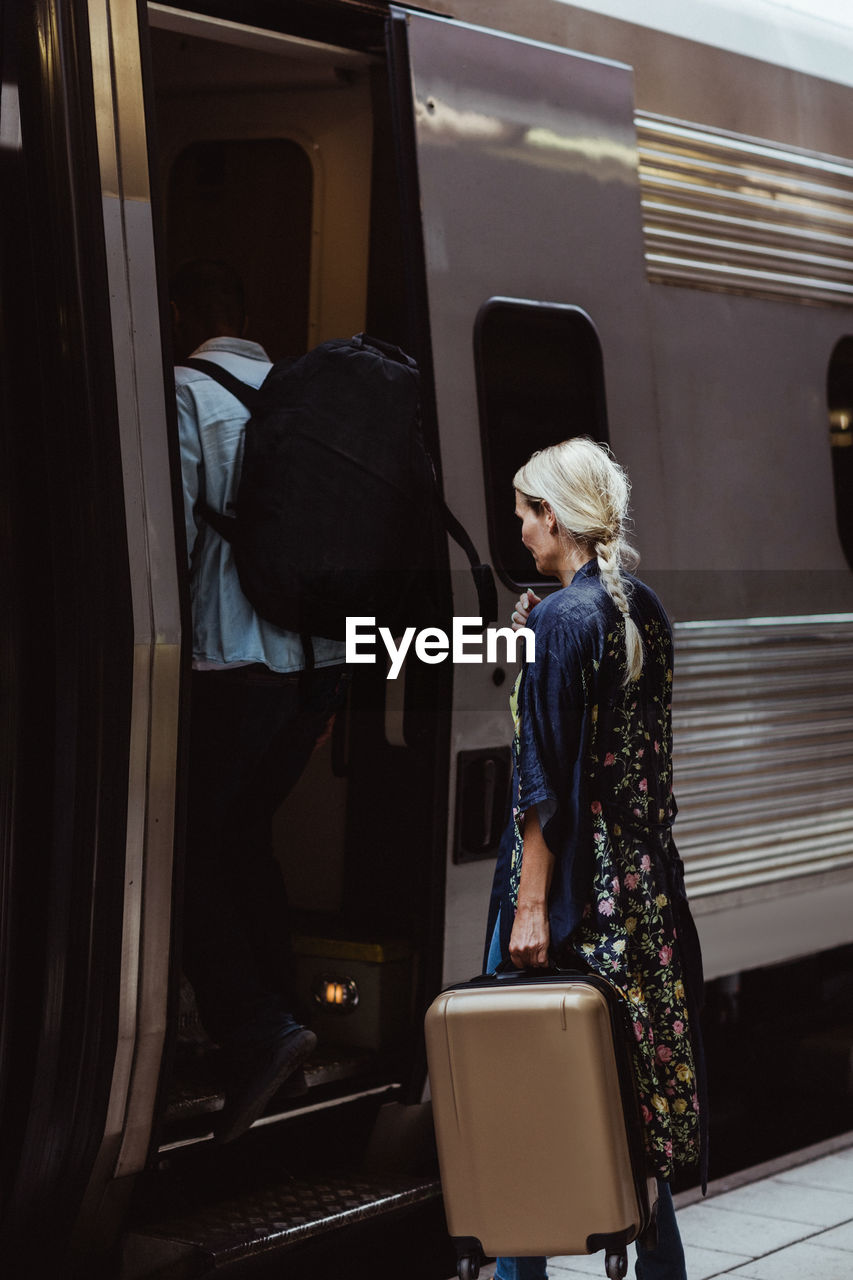 Couple with luggage boarding train at station