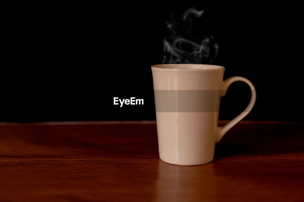 CLOSE-UP OF COFFEE SERVED ON TABLE AGAINST BLACK BACKGROUND