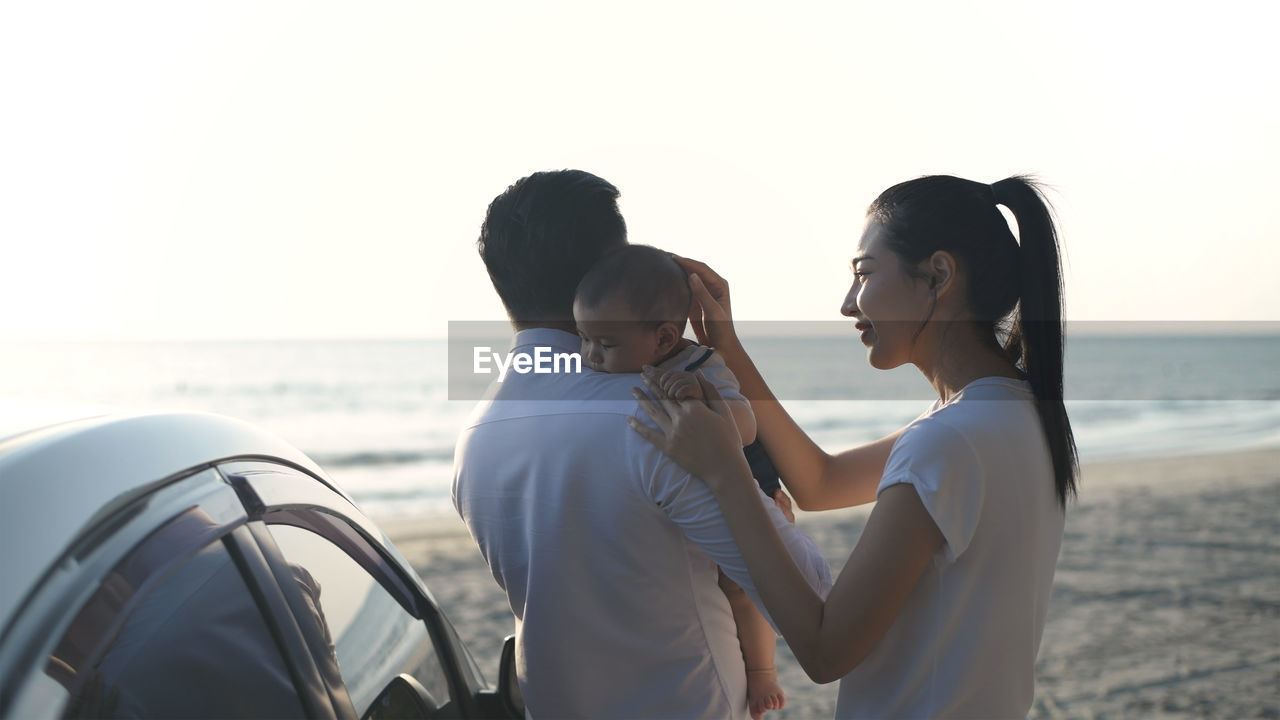 Friends standing at beach against sky