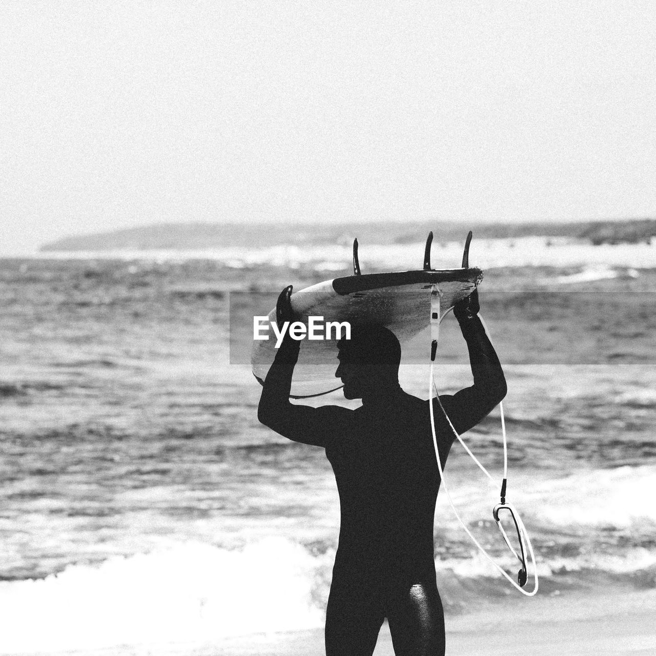 MAN STANDING ON BEACH AGAINST SEA