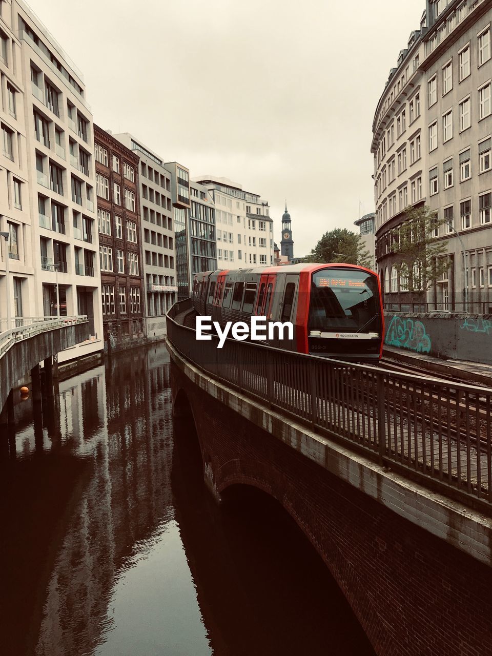 BRIDGE OVER RIVER AMIDST BUILDINGS IN CITY