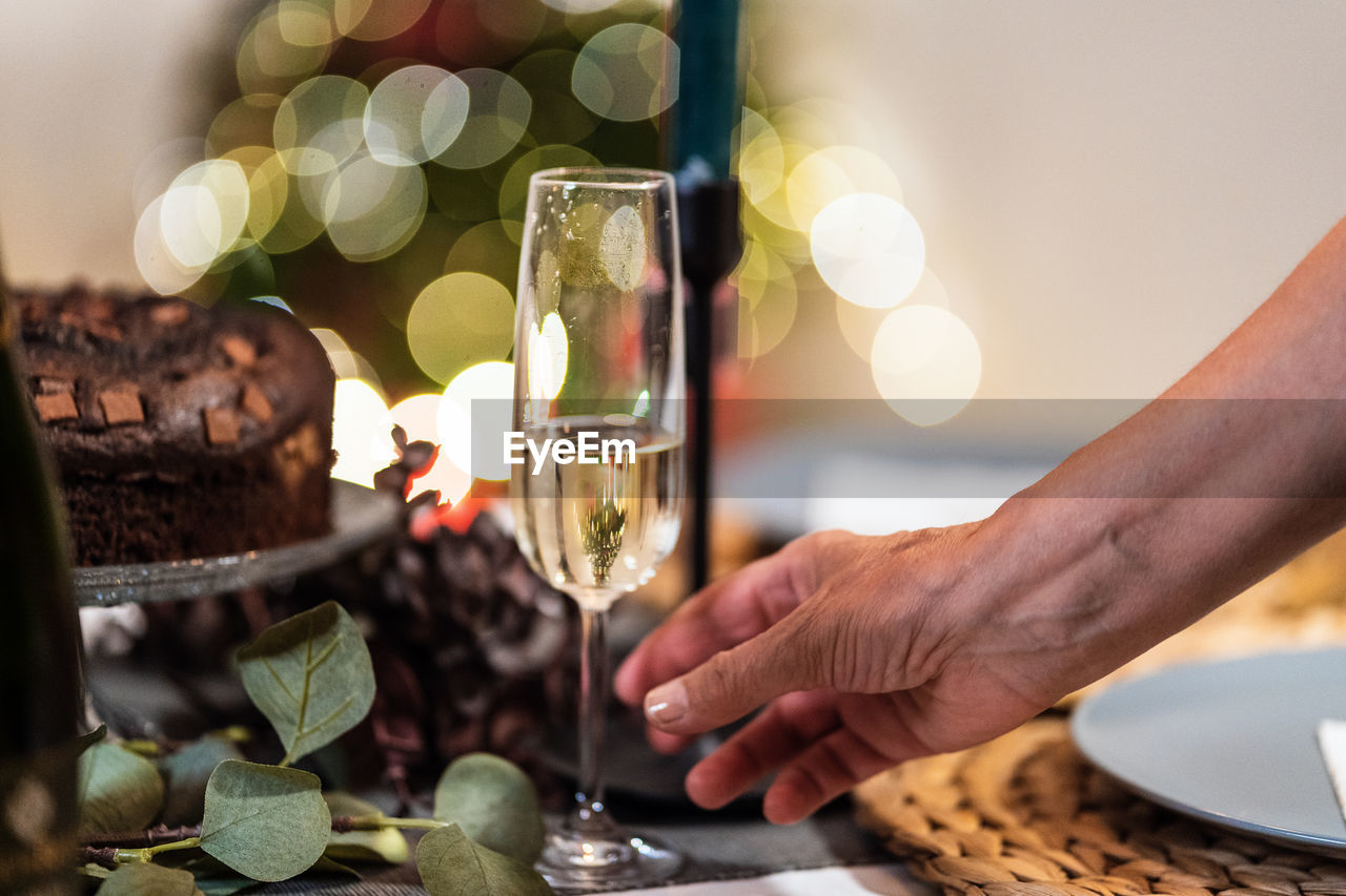 Unrecognizable female in glittering dress standing in room with glass of champagne during christmas party