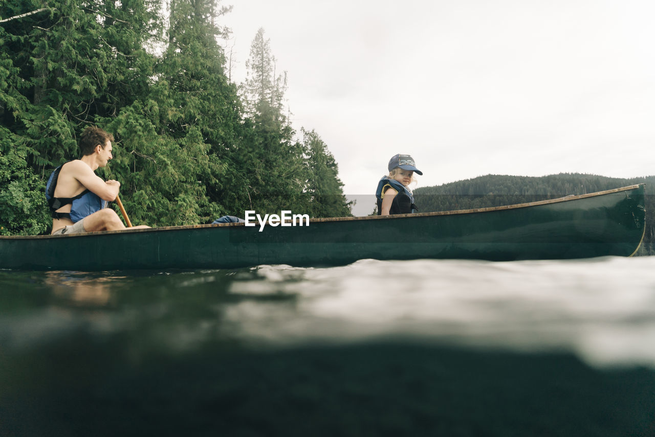 A young girl rides in a canoe with her dad on lost lake in oregon.