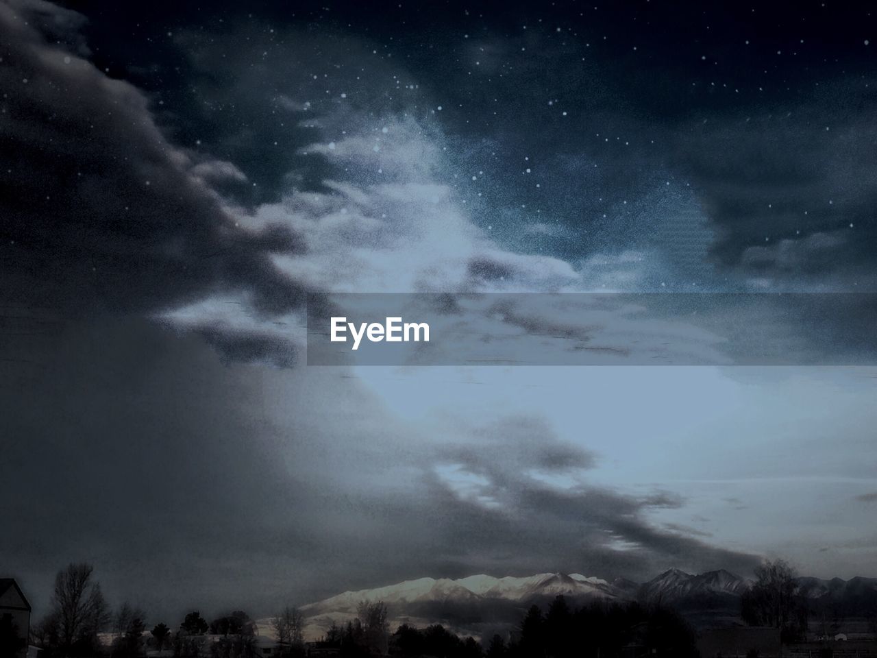 Low angle view of cloudy sky over trees