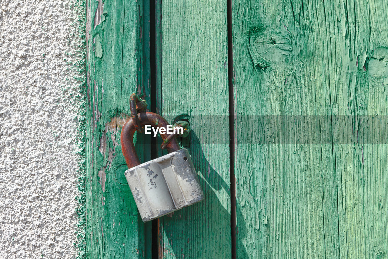 Padlock hanging on the wooden door . closed door made by planks