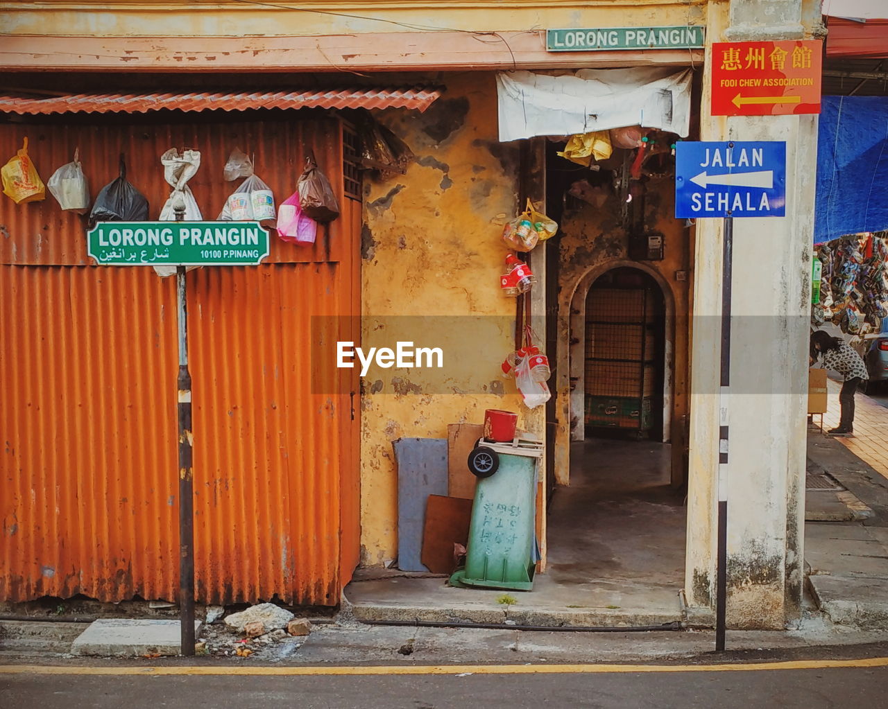 Street name sign against garbage bags on metallic wall