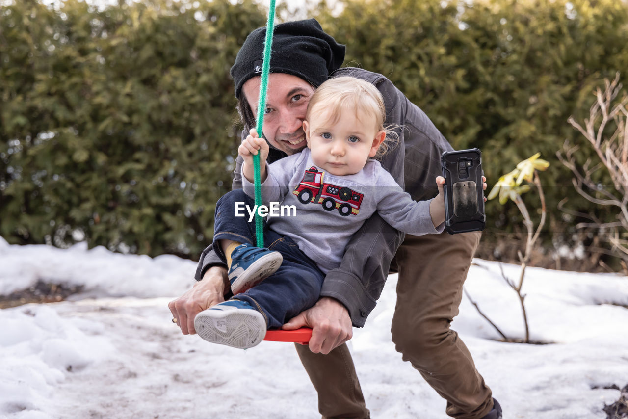 PORTRAIT OF FATHER AND SON ON DAUGHTER OUTDOORS