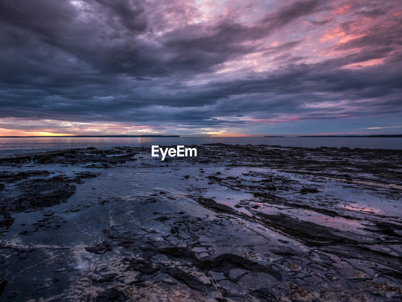 Scenic view of sea against dramatic sky during sunset