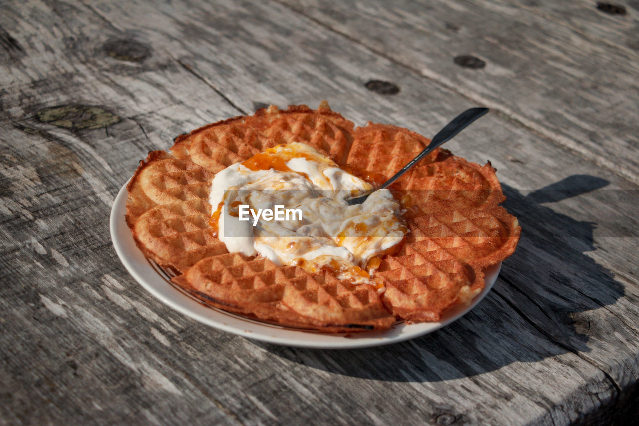 Swedish waffle with cloudberry jam and whipped cream outdoors in the autumn sun