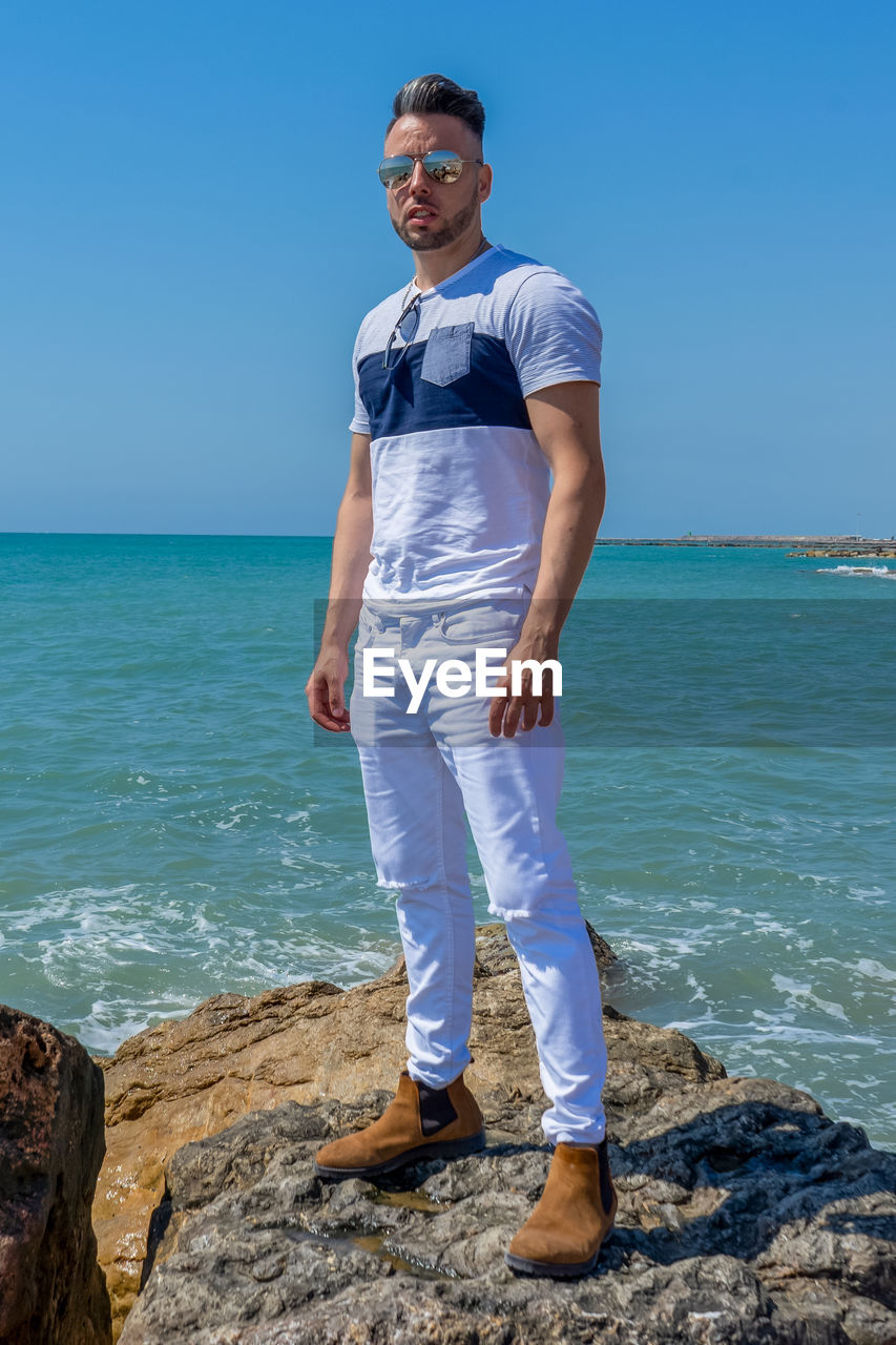 YOUNG MAN STANDING ON BEACH