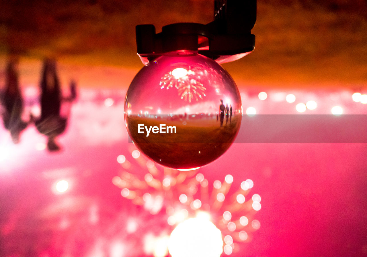 Reflection of firework display on crystal ball on field at night