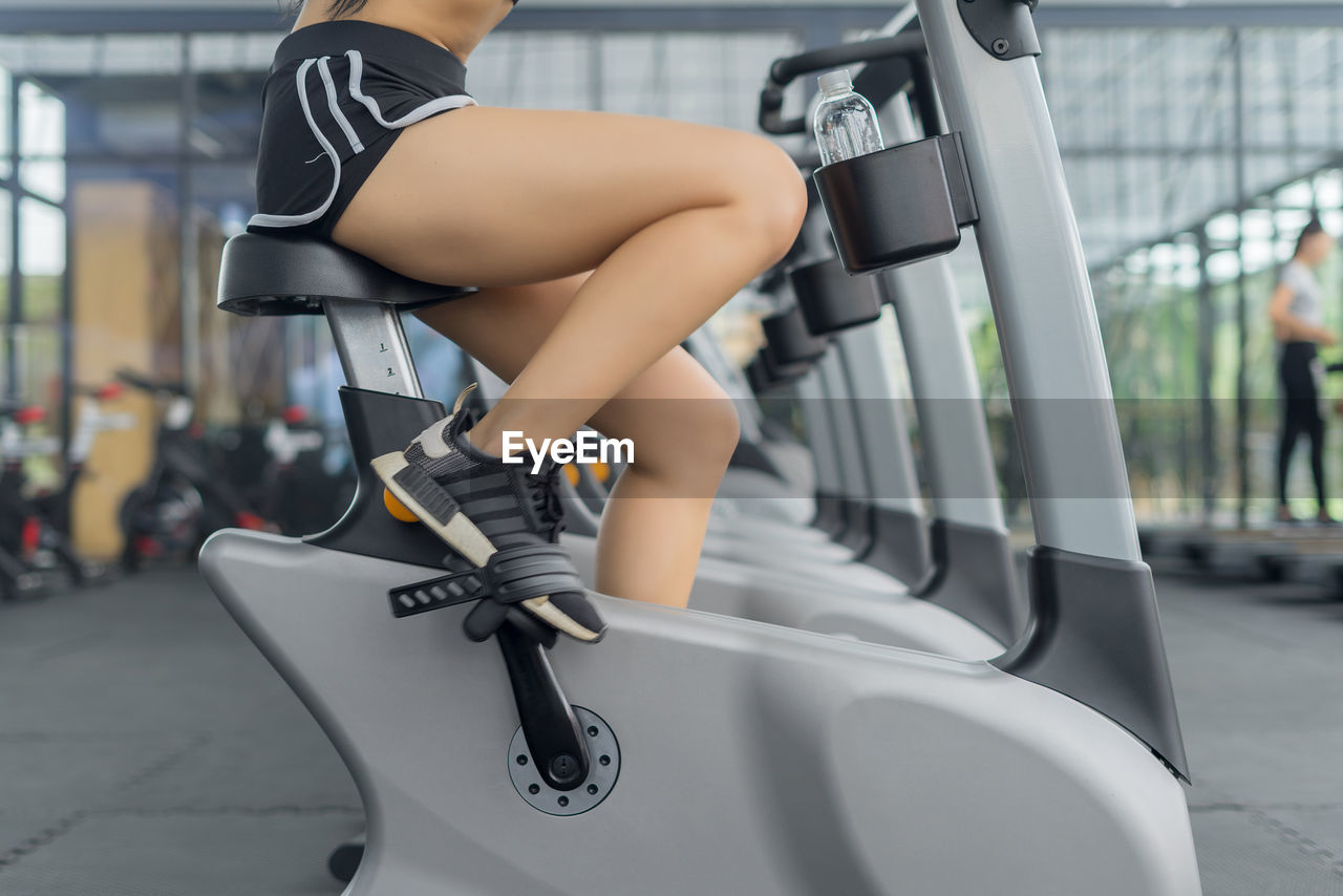 Low section of woman on exercise equipment at gym
