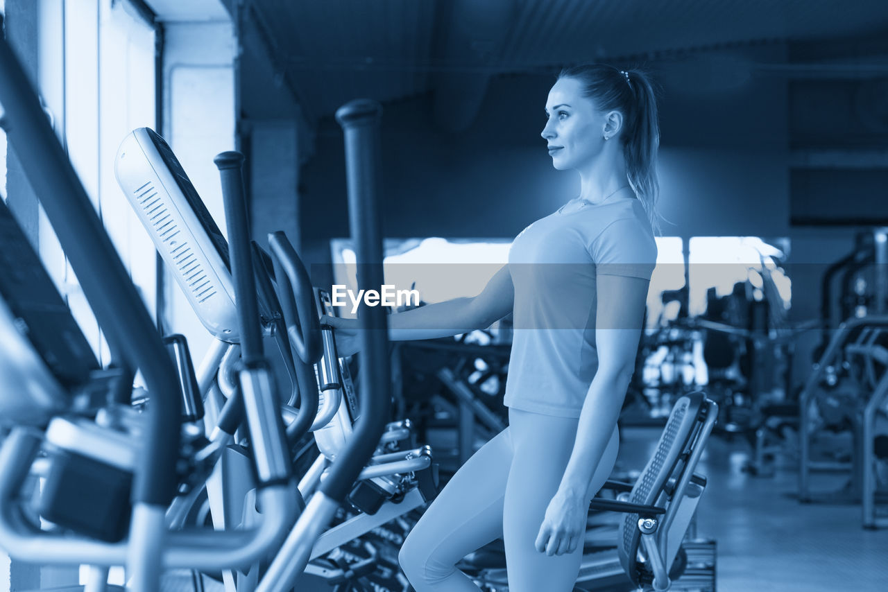 side view of young woman sitting in gym