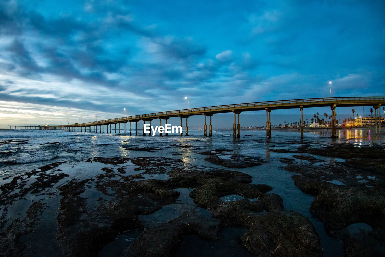 BRIDGE OVER BEACH AGAINST SKY