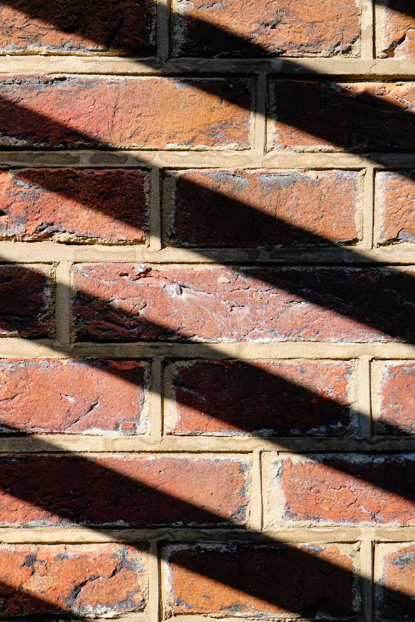 Sunshine casting a shadow pattern on a brick wall