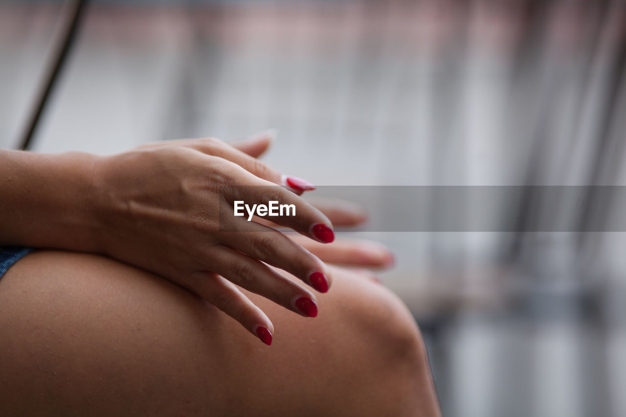 Midsection of woman with red painted fingernails