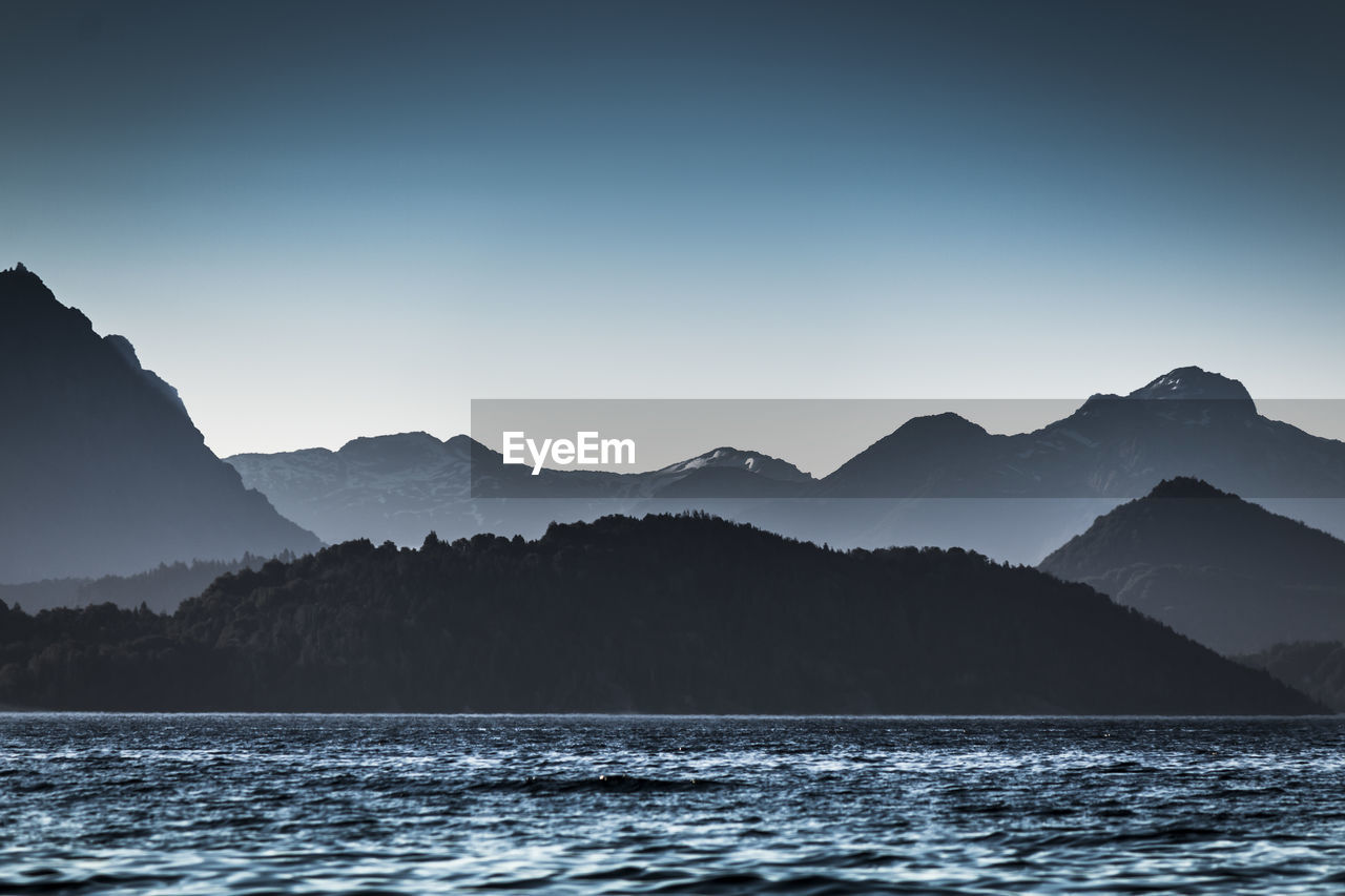 Scenic view of sea and mountains against clear sky