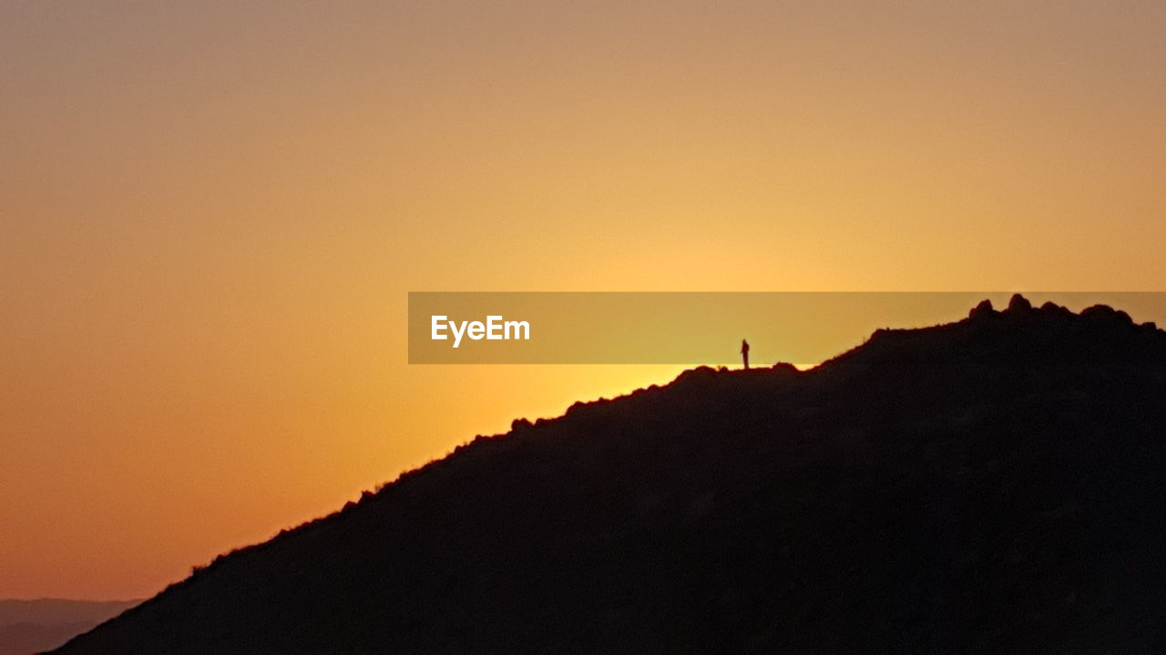 SCENIC VIEW OF SILHOUETTE MOUNTAINS DURING SUNSET