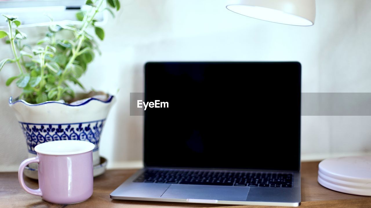 Coffee cup on table with laptop